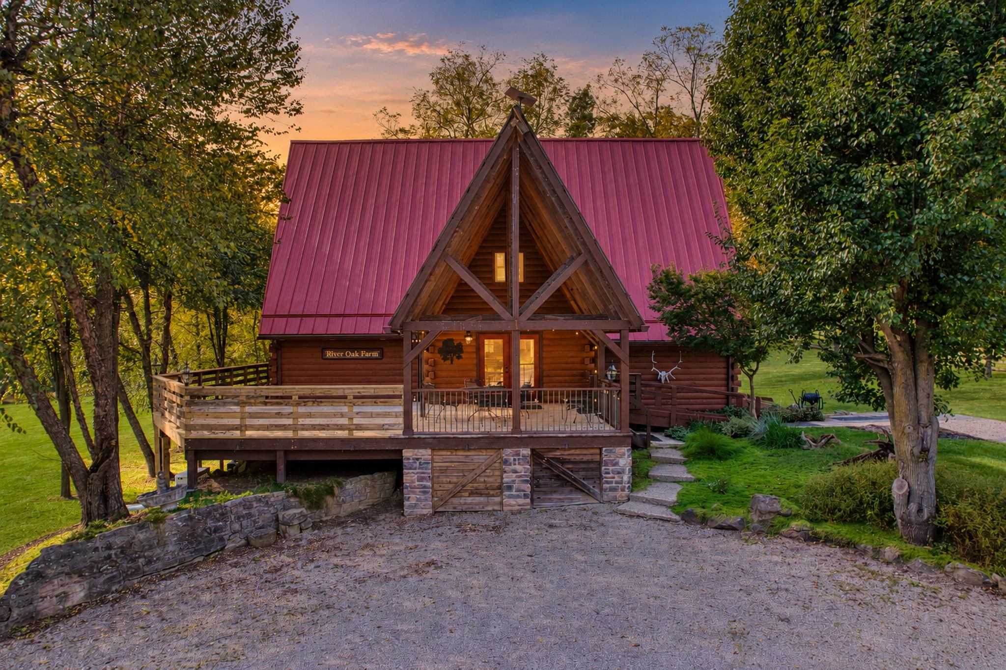 Log home with red metal roof and covered deck at twilight
