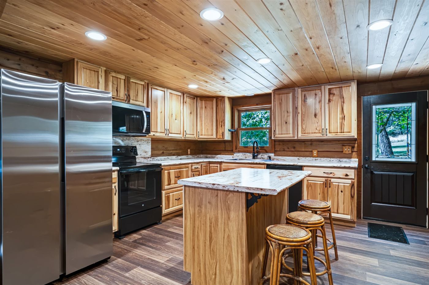Kitchen with granite island and stainless refrigerator